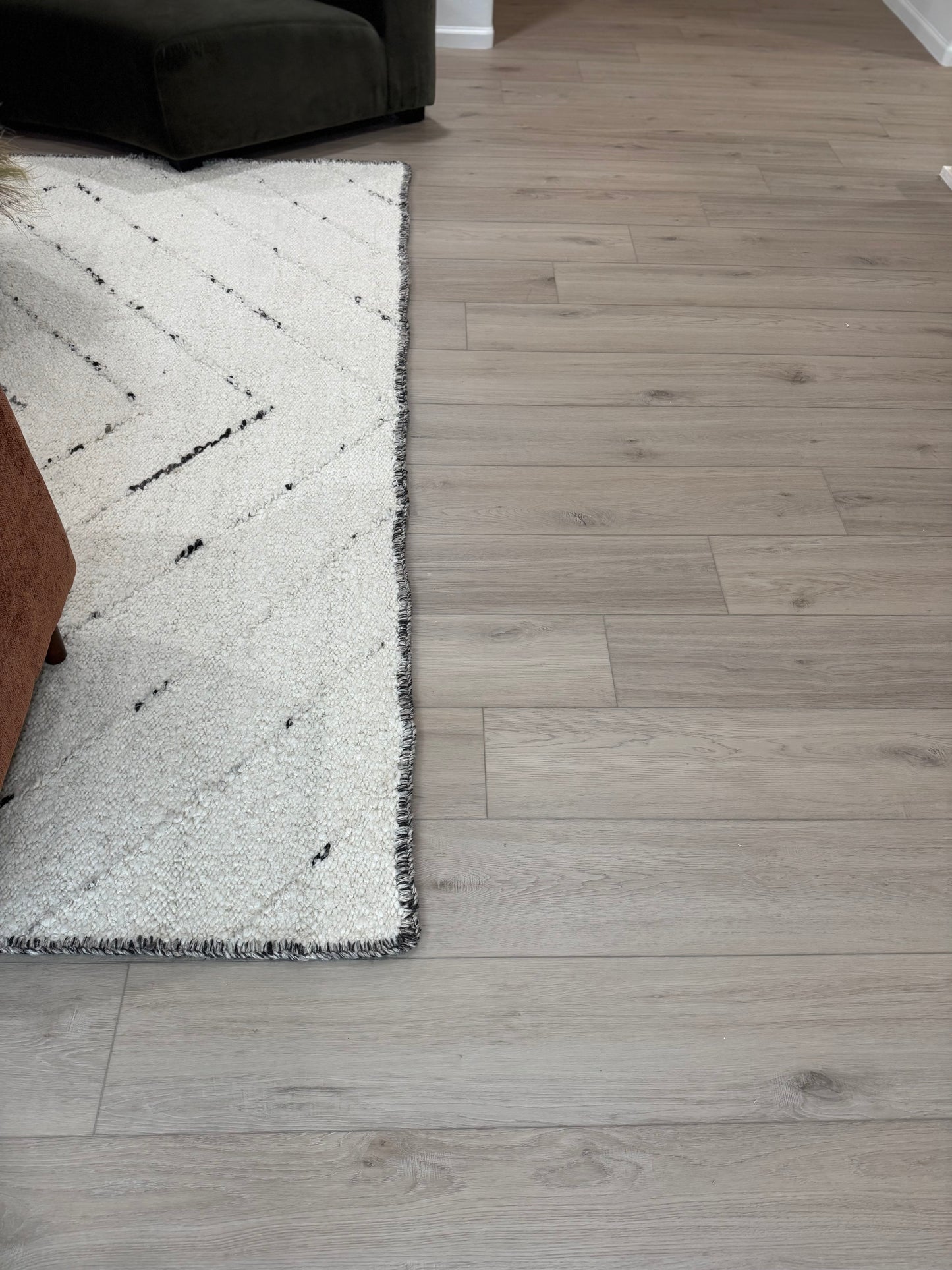 Living Room Photo of the color Meadow from the DeBoer Elite Stoneform Luxury Vinyl Plank Flooring Collection from an alternate angle with a chair and rug