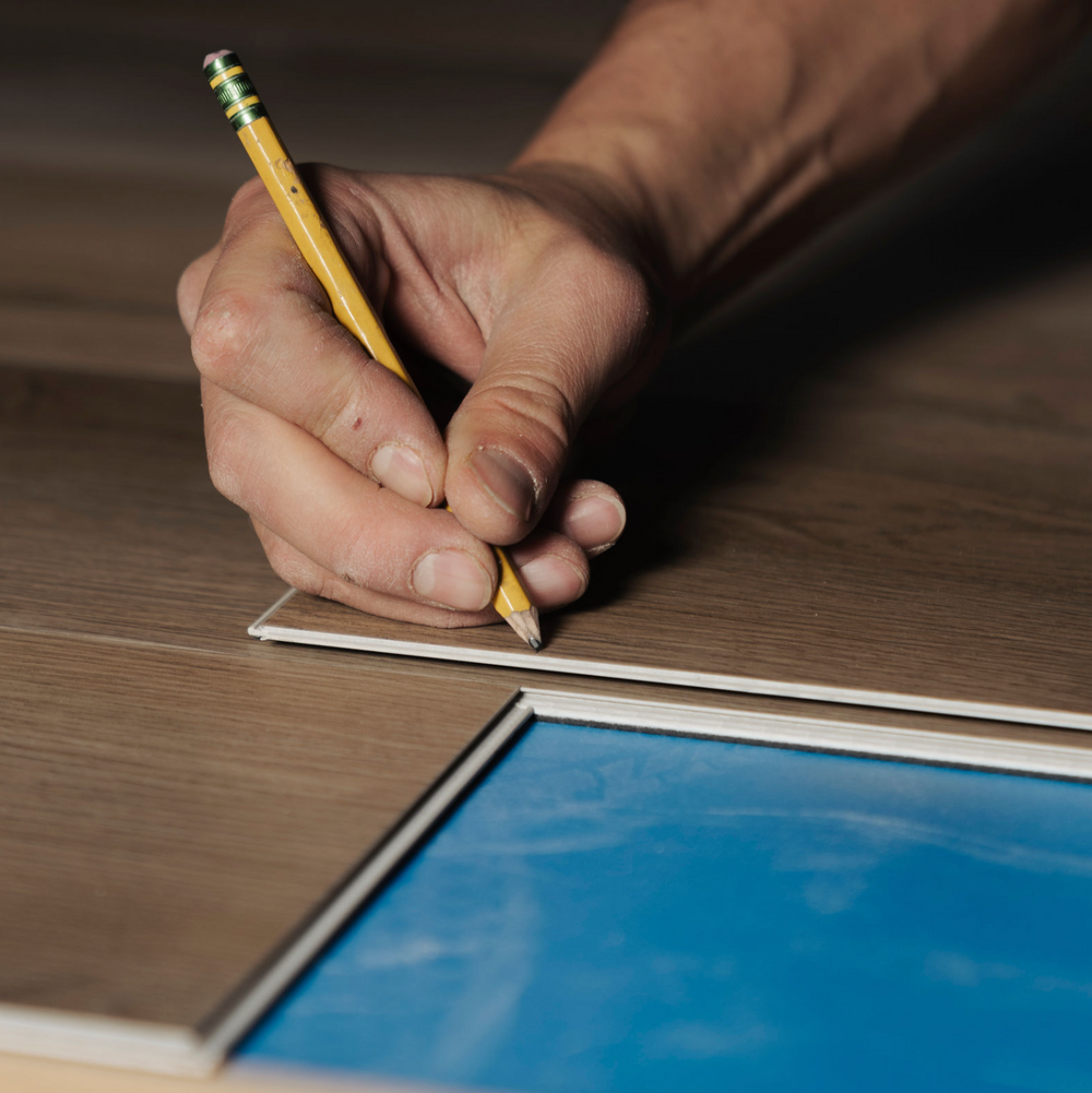Photo of a flooring installer measuring a cut on Hewn Stoneform Select Beam luxury plank flooring