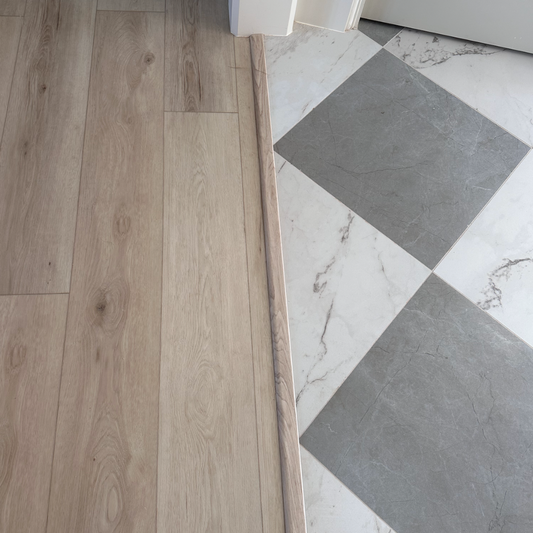 Hewn floor transition piece for floor transitioning under doorway