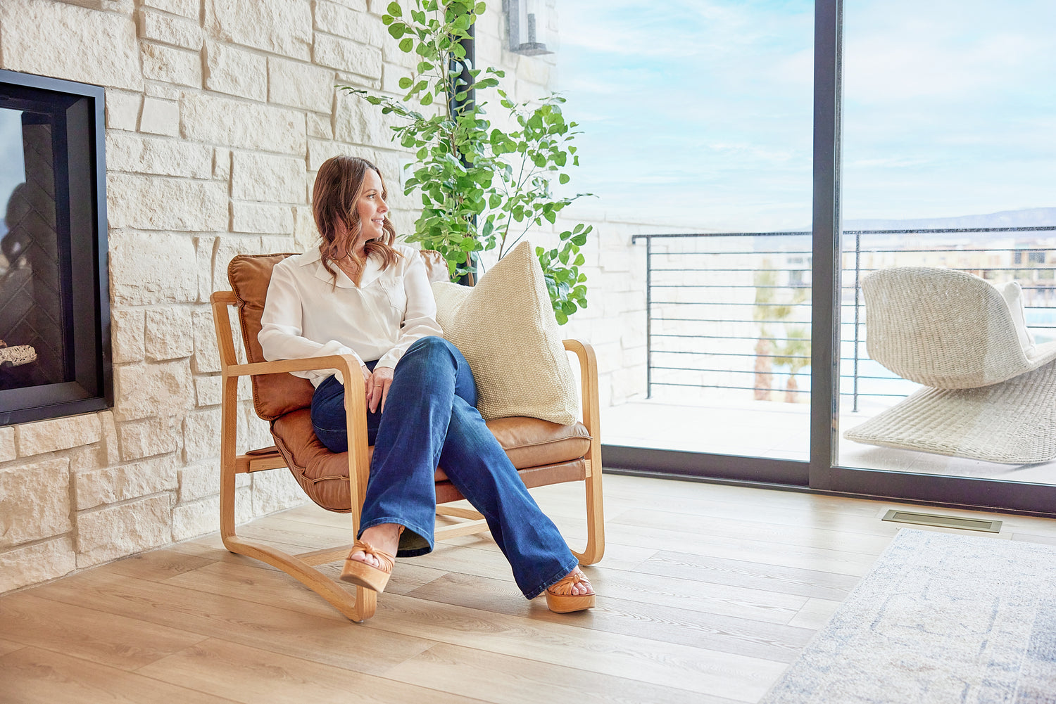 Designer Becki Owens sitting in a living room featuring her Weathered Stoneform Elite Plank Flooring